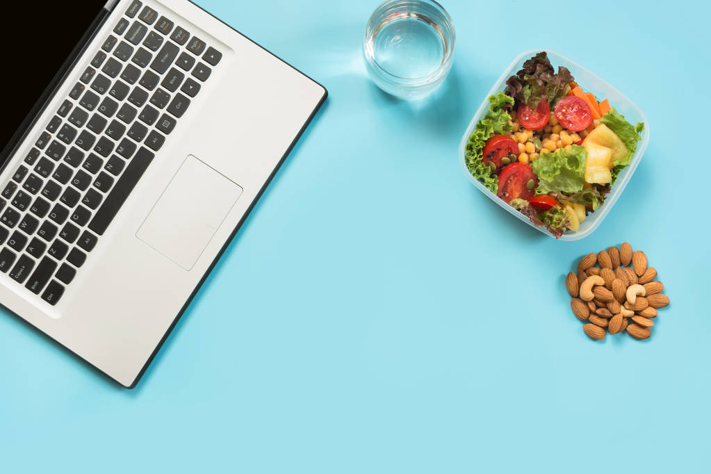 gesundes Geschäftsessen im Büro, Salat, Mandeln, Wasser auf Blau. Ansicht von oben mit Kopierraum. Konzept gesunde Ernährung. Lunchbox. - Foto, Bild