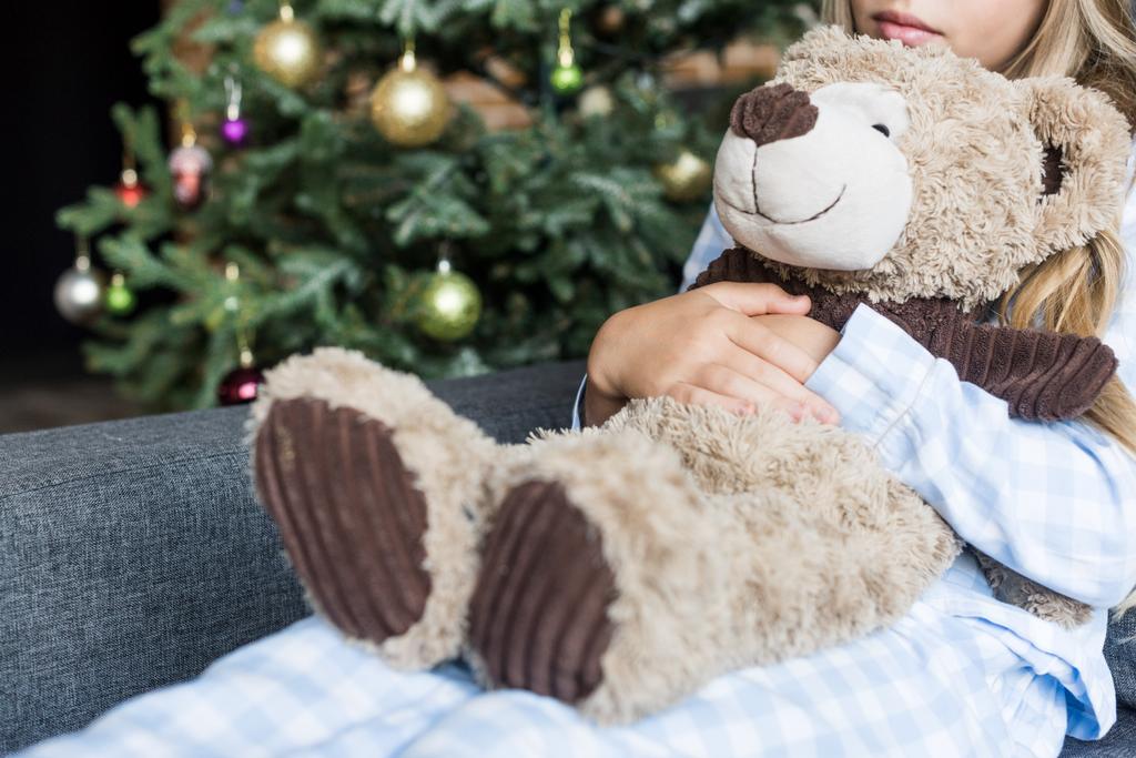 oyuncak ayı sarılma ve Noel zamanda koltukta oturan çocuk bardak kırpılmış  - Fotoğraf, Görsel