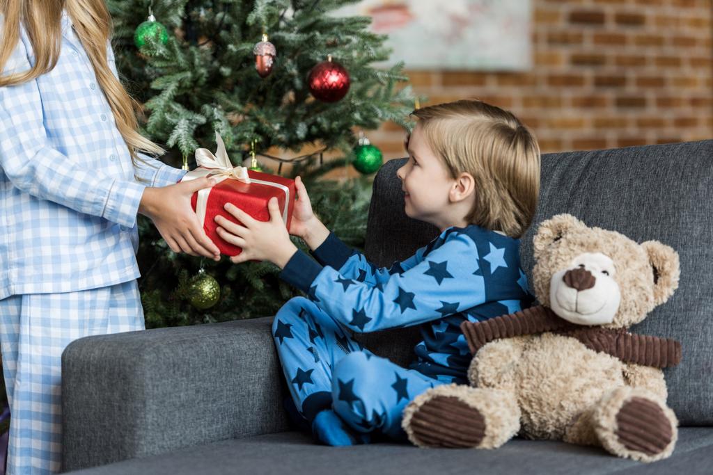 περικοπεί βολή του παιδιού παρουσιάζοντας χριστουγεννιάτικο δώρο αξιολάτρευτο χαμογελαστός ο αδελφός   - Φωτογραφία, εικόνα