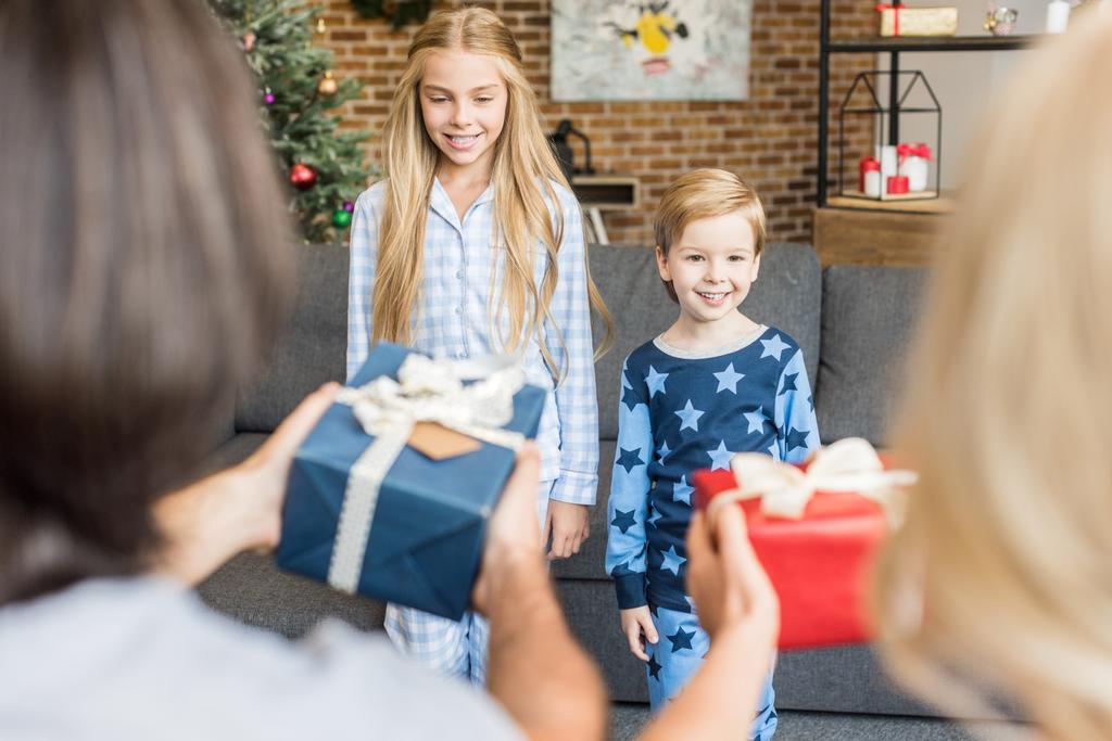 вибірковий фокус батьків, що представляють різдвяні подарунки щасливим дітям у піжамах
  - Фото, зображення