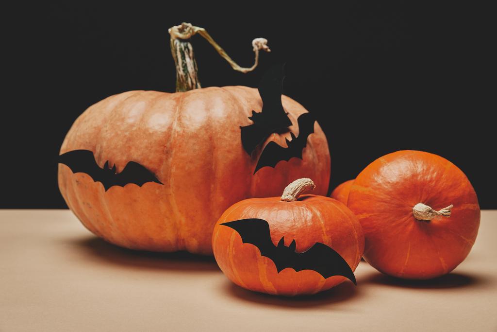 Üç turuncu halloween pumpkins ile masa üzerinde kağıt yarasalar - Fotoğraf, Görsel