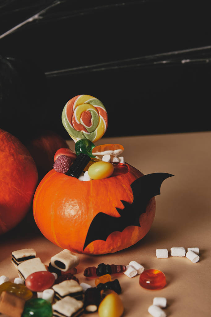 pumpkins, paper bat and candies on table, halloween concept - Photo, Image