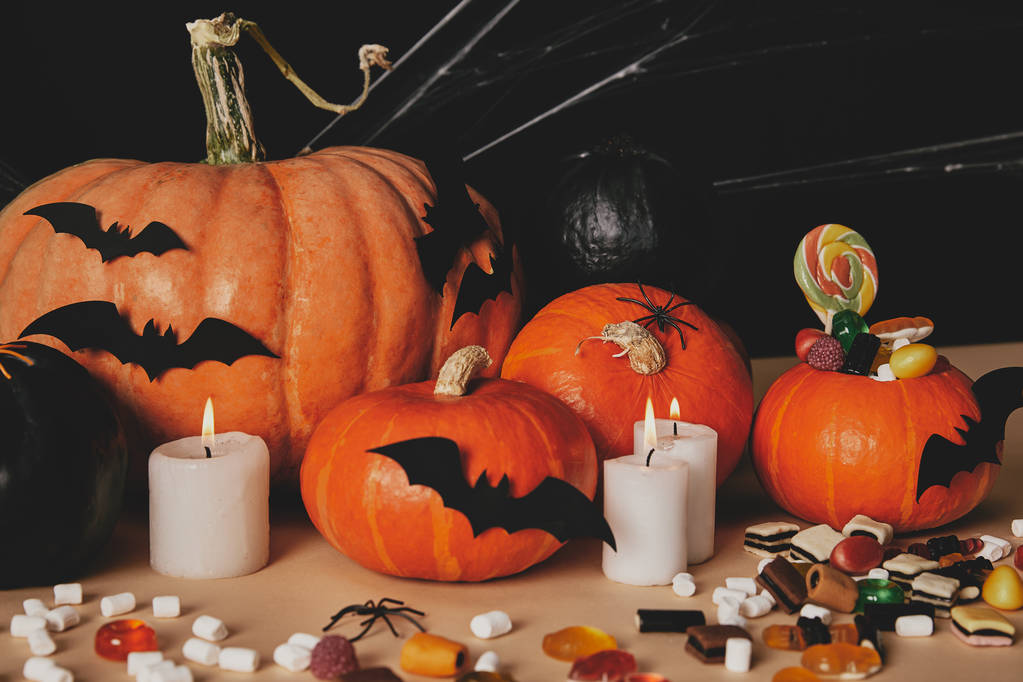 pumpkins, jelly candies, marshmallows and paper bats on table, halloween concept - Photo, Image