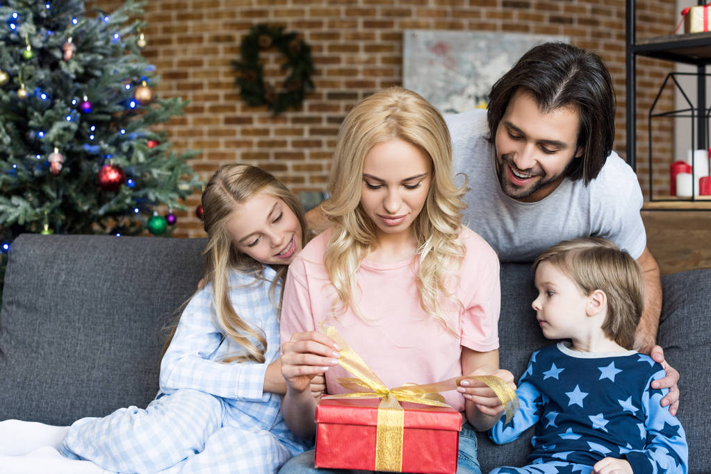ευτυχής πατέρας με δύο λατρευτά παιδιά βλέπουν μητέρα εγκαίνια χριστουγεννιάτικο δώρο στο σπίτι  - Φωτογραφία, εικόνα