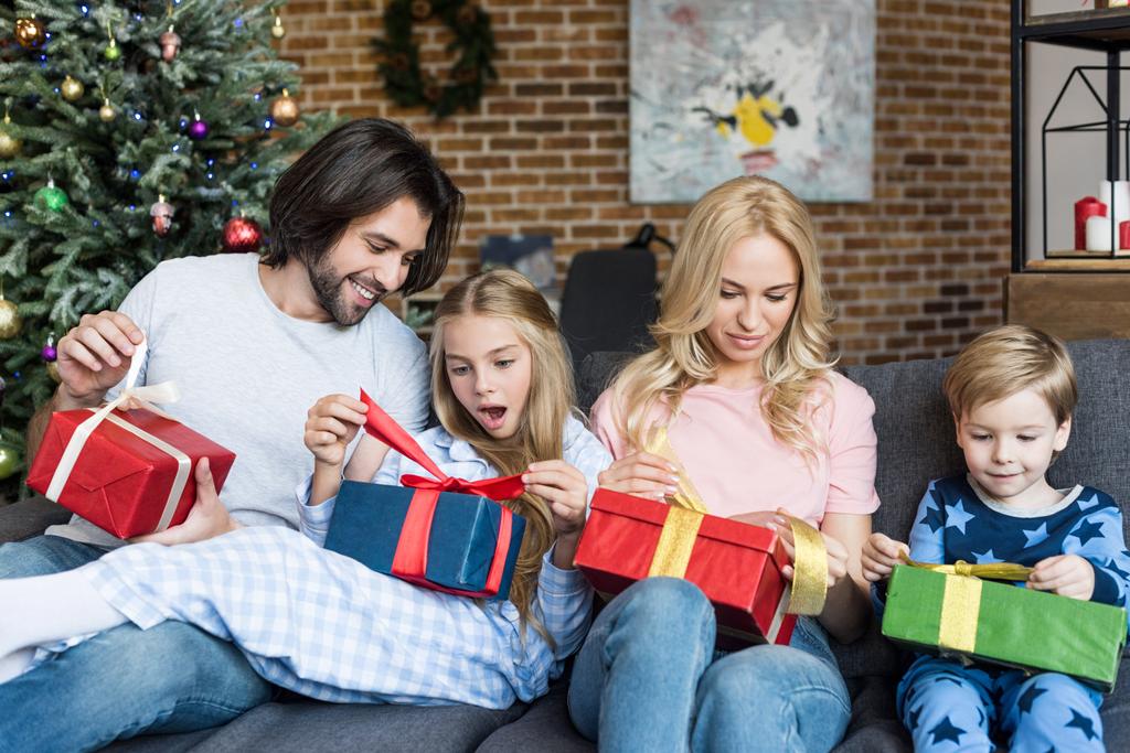 ευτυχισμένη οικογένεια με δύο αξιολάτρευτα πιτσιρίκια άνοιγμα χριστουγεννιάτικα δώρα μαζί - Φωτογραφία, εικόνα