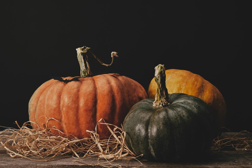 drei reife Kürbisse und Papierfledermaus auf dem Tisch, Halloween-Konzept - Foto, Bild