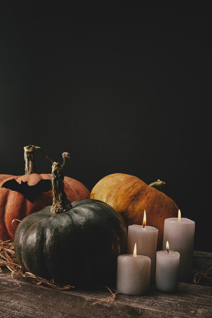 pompoenen, vleermuizen van zwart papier en kaarsjes op tafel, halloween concept - Foto, afbeelding