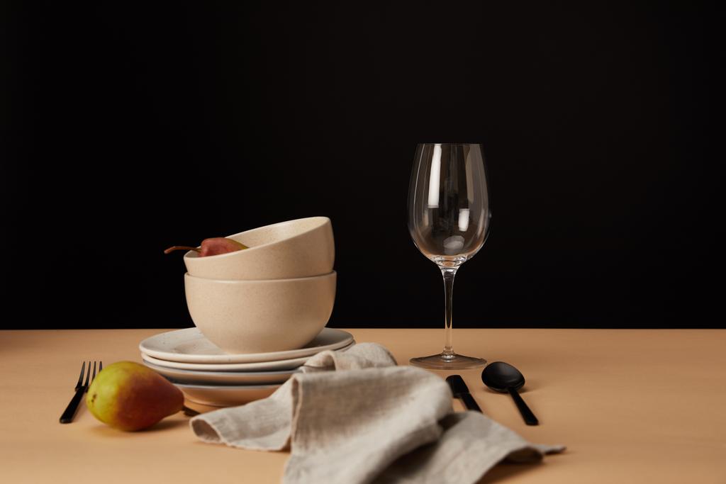 borden, kommen, wijnglas, servet en peren op beige tafel - Foto, afbeelding