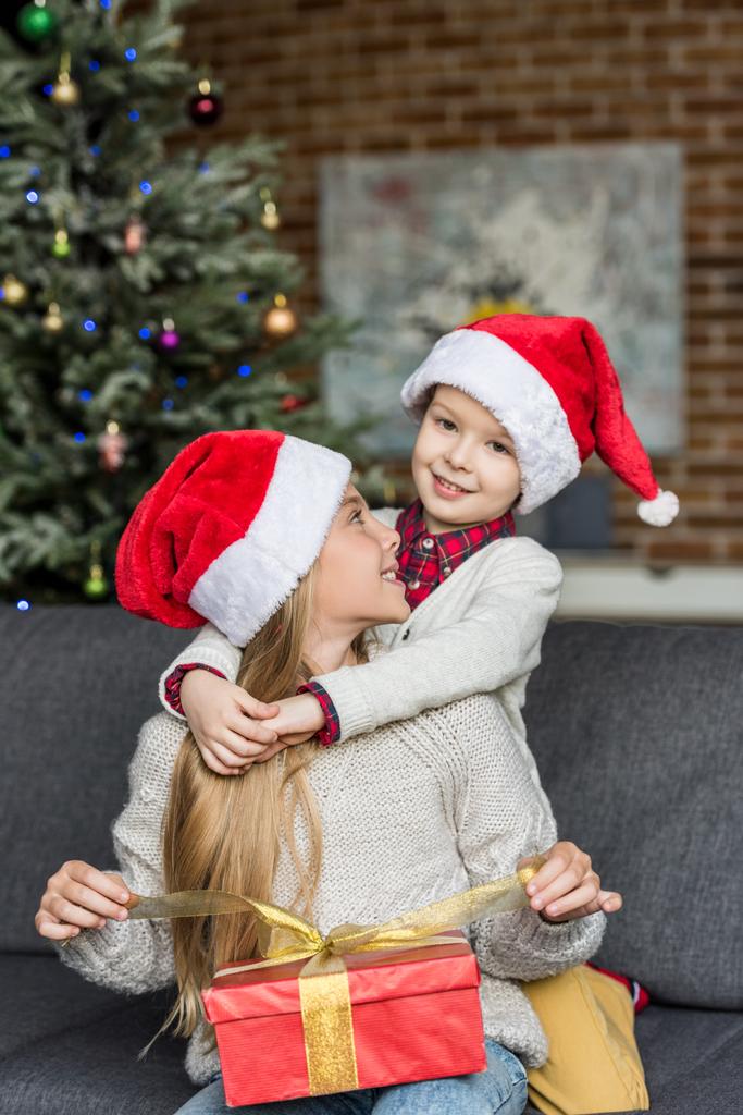 feliz hermano y hermana en los sombreros de santa abrazo y apertura regalo de Navidad
 - Foto, imagen