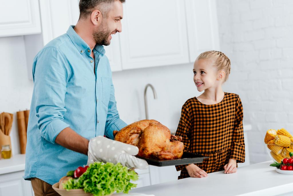 отец и очаровательная маленькая дочь пекут индейку на ужин в честь Дня Благодарения
 - Фото, изображение