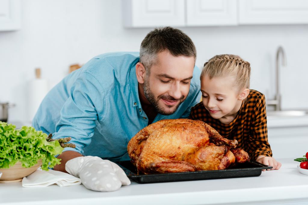 onnellinen isä ja tytär haistavat juuri leivottua kiitospäivän kalkkunaa
 - Valokuva, kuva
