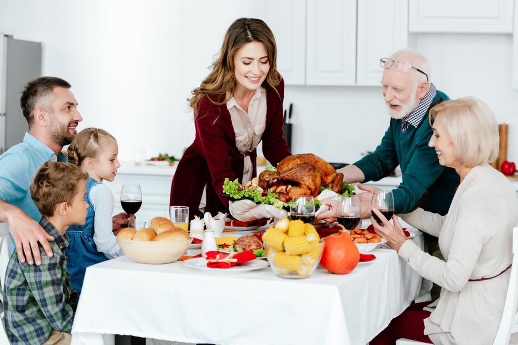 adult woman and senior man carrying baked turkey for thanksgiving dinner with family  - Photo, Image