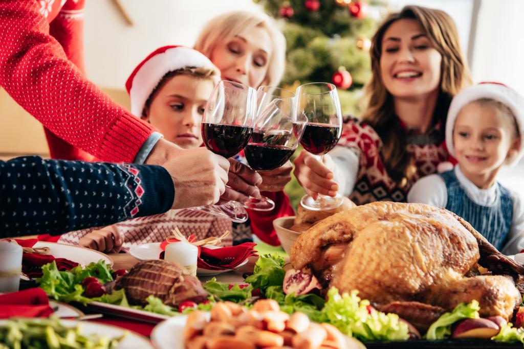 imagem cortada de família clinking por copos de vinho durante o jantar de Natal em casa
  - Foto, Imagem