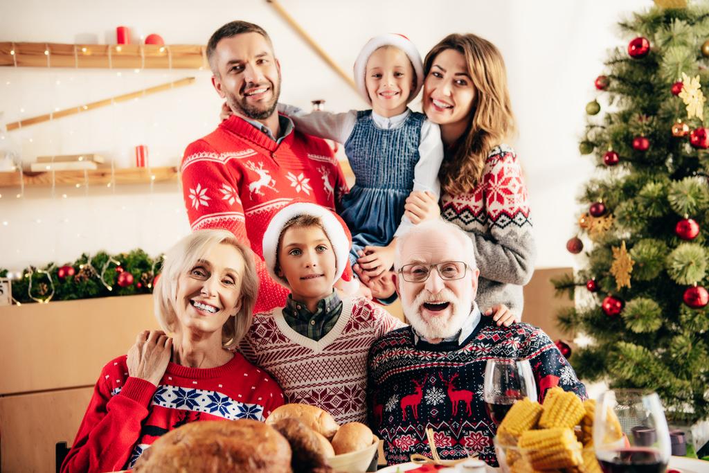 χαμογελαστός, μεγάλη οικογένεια με παιδιά Χριστούγεννα καπέλα γιορτάζει στο τραπέζι με δείπνο διακοπές στο σπίτι - Φωτογραφία, εικόνα