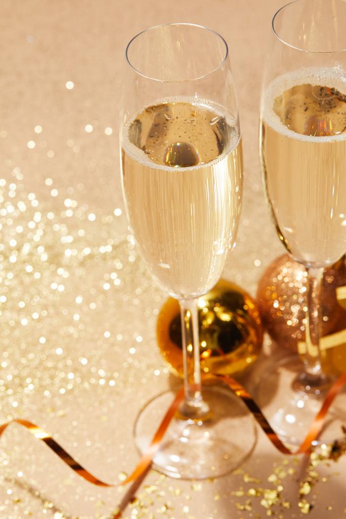 primer plano de dos copas de champán y juguetes de Navidad con purpurina en la mesa
 - Foto, imagen