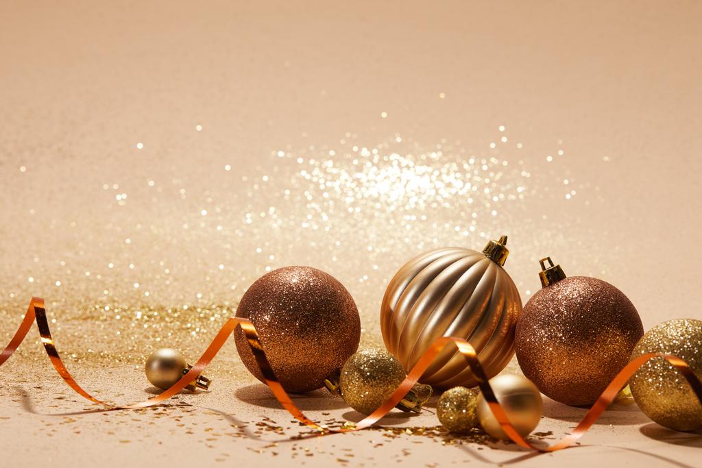 boules de Noël brillantes scintillantes et ruban ondulé sur plateau beige
 - Photo, image