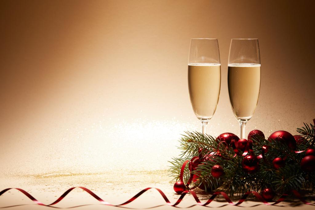 glasses of champagne, christmas balls and pine branch on glittering tabletop - Photo, Image