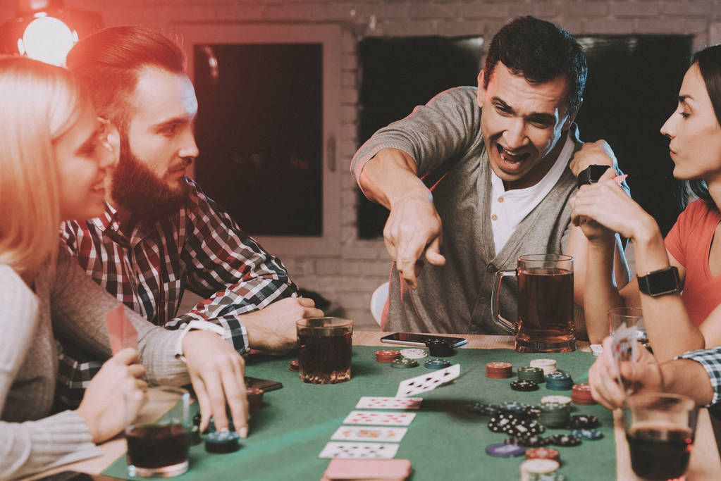 Νέους φίλους παίζοντας πόκερ στο συμβαλλόμενο μέρος στο σπίτι. Παίζοντας παιχνίδια. Διασκέδαση εσωτερικού χώρου. Νεαρή κοπέλα. Ο νεαρός άντρας. Κάθεται στο τραπέζι. Πάρτι με τους φίλους σας. Εσωτερική δραστηριότητες έννοια. Τα τυχερά παιχνίδια. Παιχνίδια τράπουλας. - Φωτογραφία, εικόνα