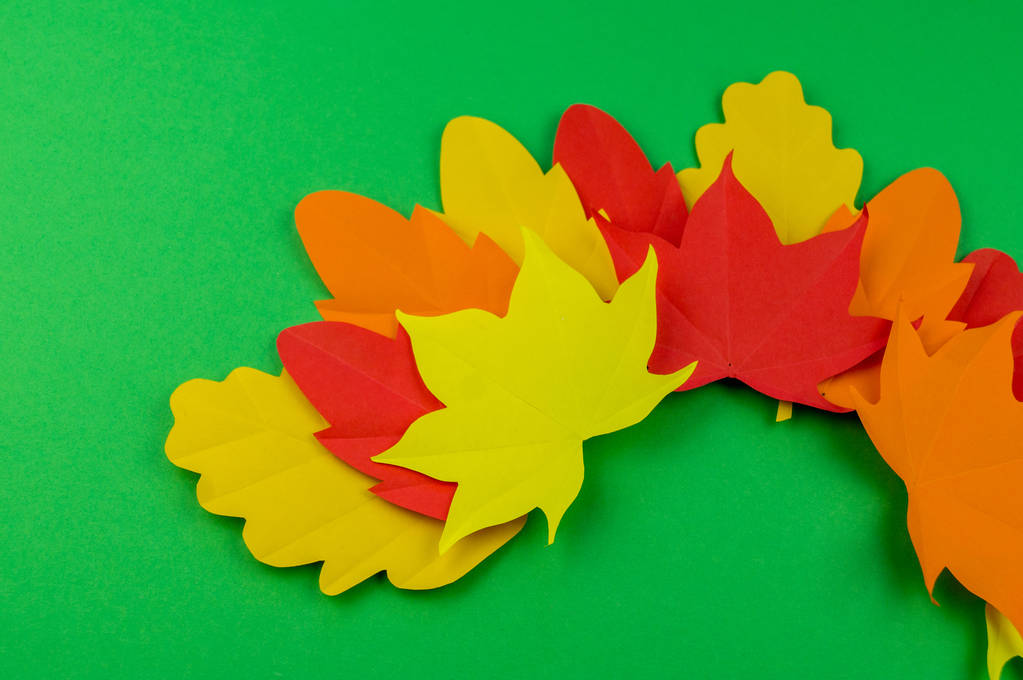 Bladeren van papier herfst. Rood, geel en oranje bladeren. Plek voor opname. Groene achtergrond. - Foto, afbeelding