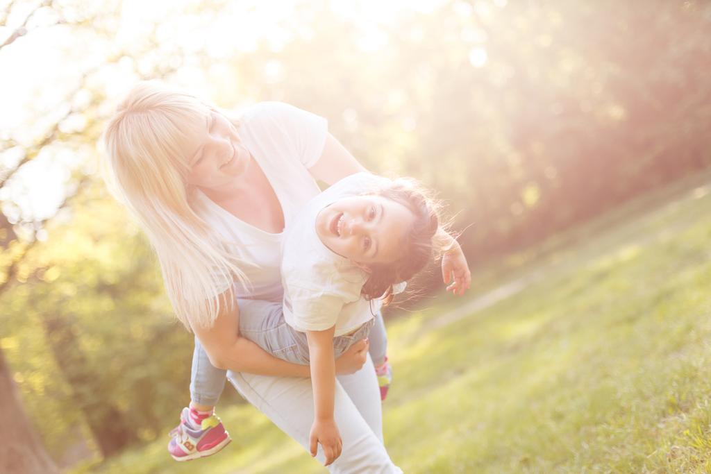 Молодая мама и веселая очаровательная девушка веселятся вместе в парке летом
 - Фото, изображение