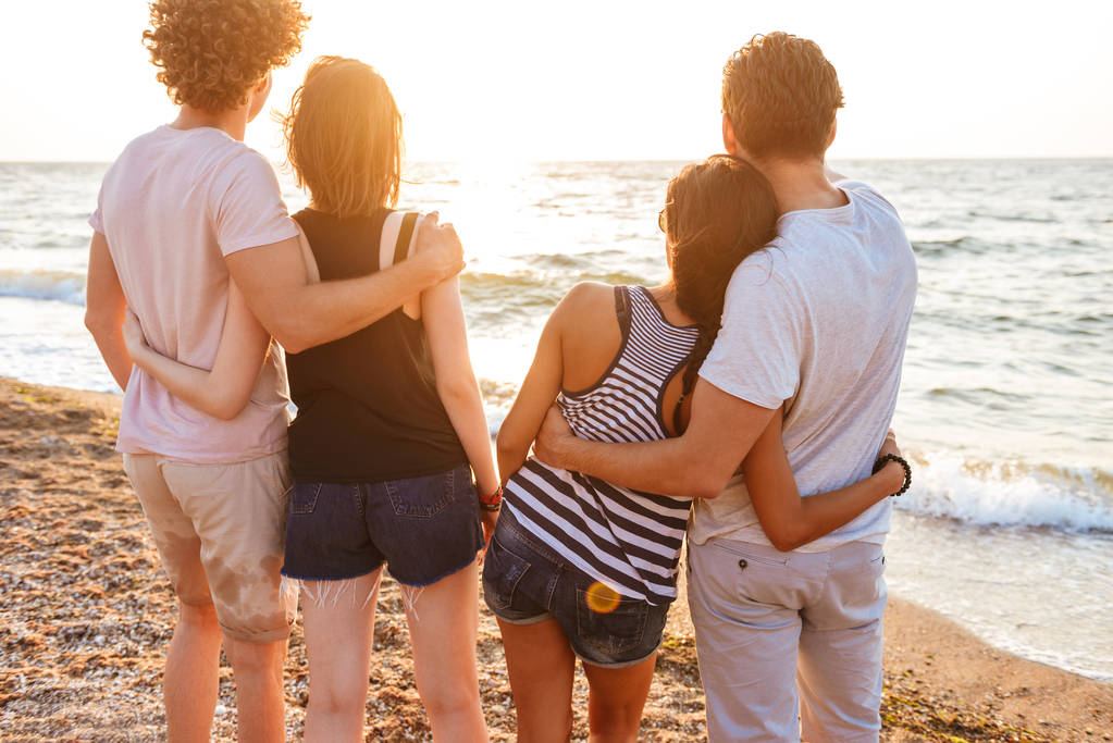 Bild von der Rückseite der glücklichen Gruppe von Freunden, die Paare lieben, die draußen am Strand spazieren gehen und Spaß haben. - Foto, Bild