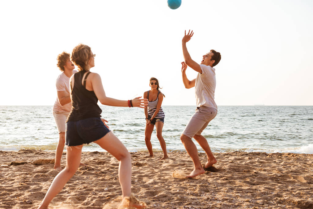 Фото счастливых друзей на пляже, играющих в волейбол
. - Фото, изображение