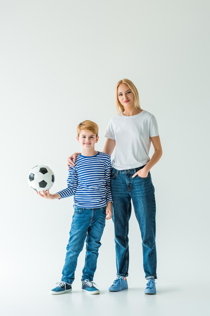 Anne ve oğlu beyaz futbol topu ile ayakta ve kameraya bakıyor  - Fotoğraf, Görsel