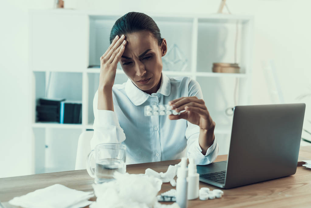 Young Sick Woman in White Shirt Sitting in Office.Healthcare Concept. Modern Office. Sick Worker. Healthcare in Office. Wooden Table. Digital Device. Laptop on Desk. Young Woman in Office. - Photo, Image