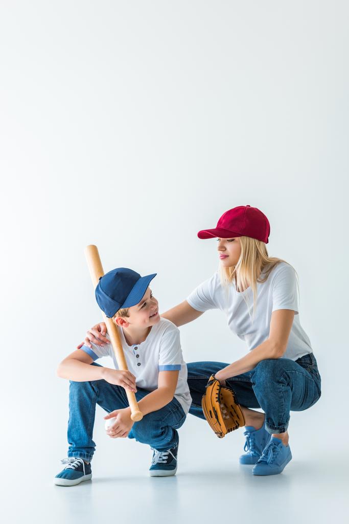 madre e hijo en cuclillas con bate de béisbol y guante en blanco
  - Foto, Imagen