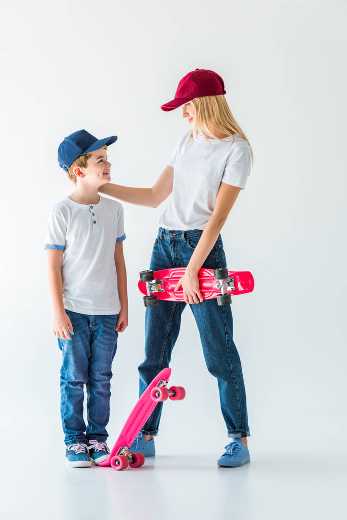 mère et fils en casquettes debout avec des patins et se regardant sur blanc
 - Photo, image