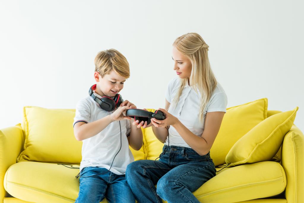 mère et fils tenant écouteurs sur canapé jaune isolé sur blanc
 - Photo, image