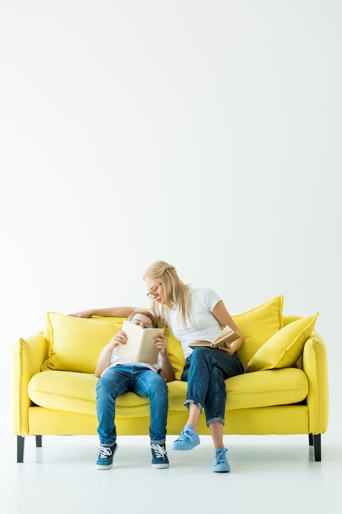 mamá e hijo leyendo libro sobre sofá amarillo sobre blanco
 - Foto, Imagen