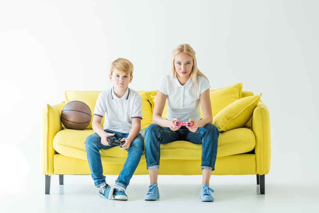 深刻な母と息子が黄色のソファの上のバスケット ボールのビデオゲームを再生 - 写真・画像