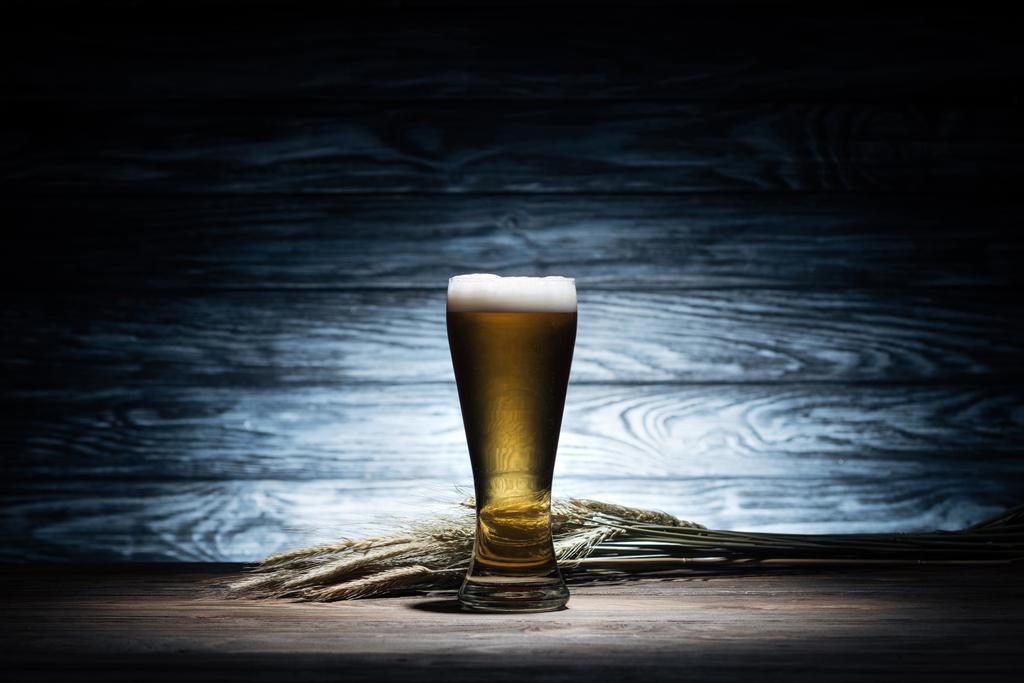 glass of tasty beer and wheat spikelets on wooden table, oktoberfest concept - Photo, Image