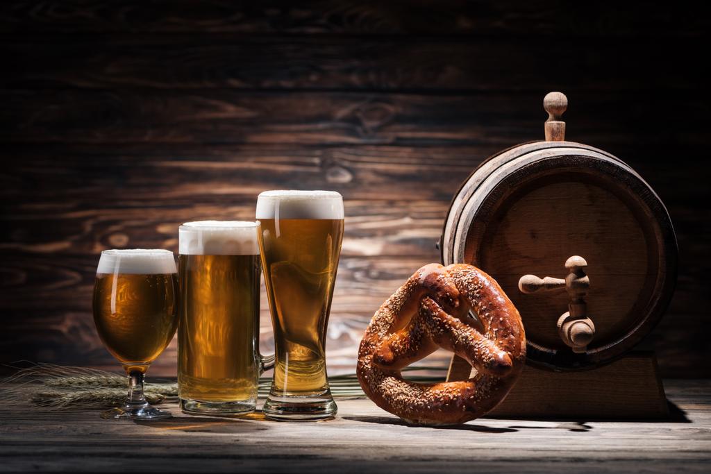 Biergläser, leckere Brezel und Bierfass auf Holztisch, Oktoberfest-Konzept - Foto, Bild