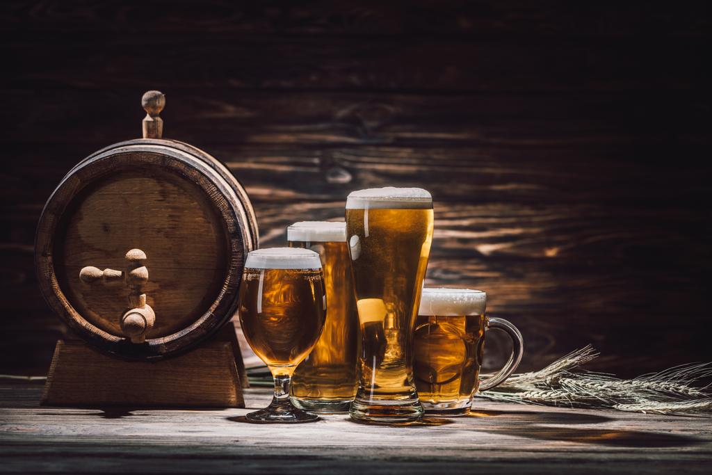 beer in glasses, wheat spikelets and beer barrel on wooden table, oktoberfest concept - Photo, Image