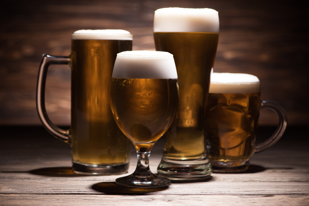 vier glazen smakelijke bier op houten tafelblad, oktoberfest concept - Foto, afbeelding