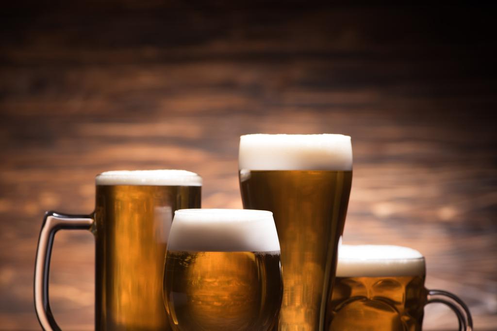 vier Gläser leckeres Bier auf hölzernem Hintergrund, Oktoberfestkonzept - Foto, Bild