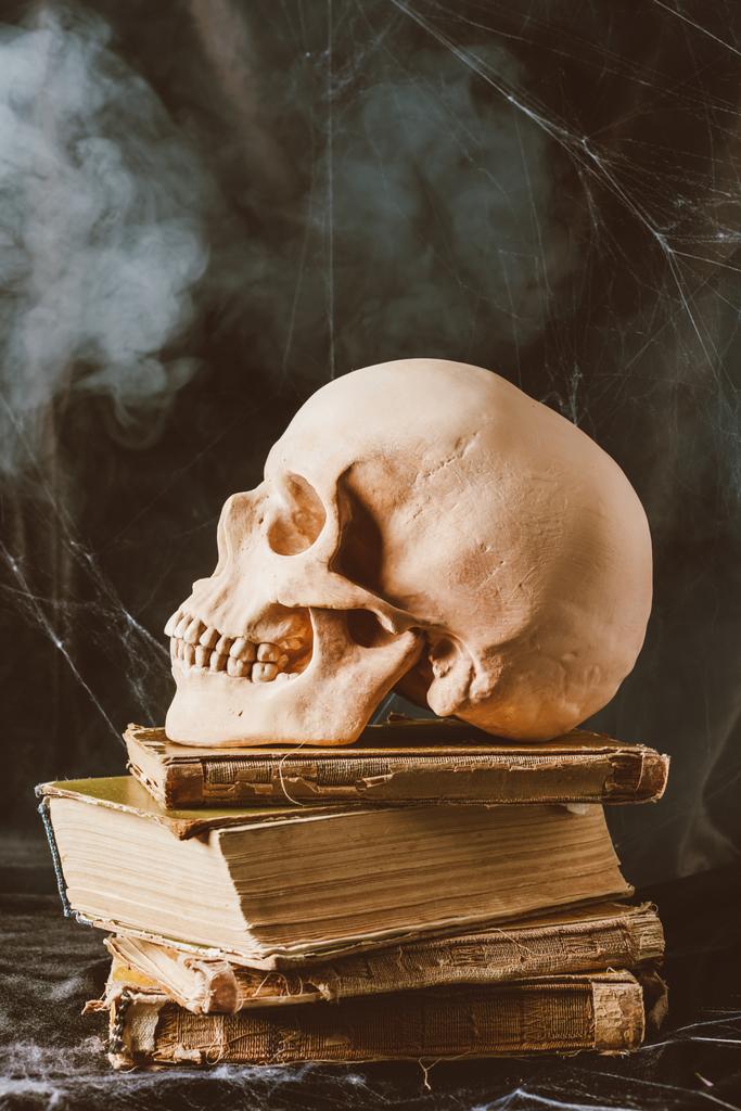 череп Хэллоуина на древних книгах на черной ткани с дымом
 - Фото, изображение