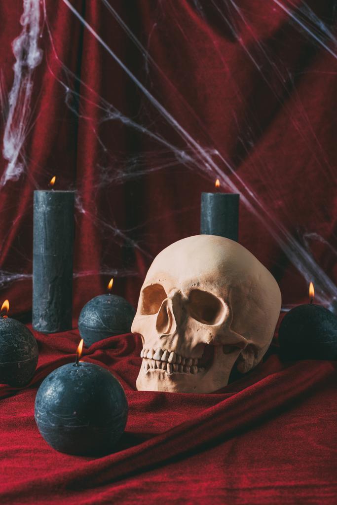 череп и черные свечи на красной ткани с паутиной для Хэллоуина
 - Фото, изображение