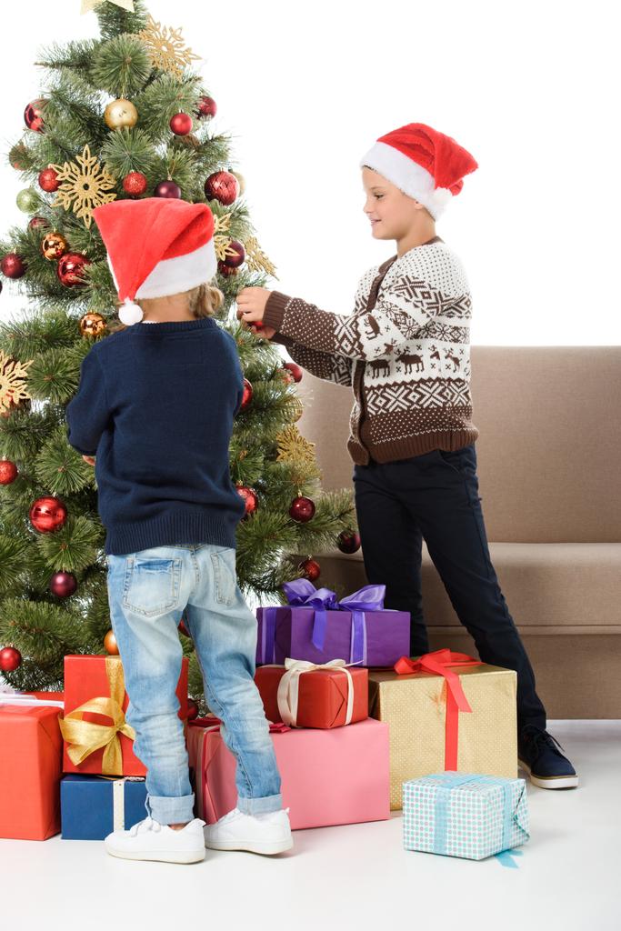 ギフト用の箱、白で隔離とクリスマス ツリーを飾るサンタ帽子の子どもたち - 写真・画像