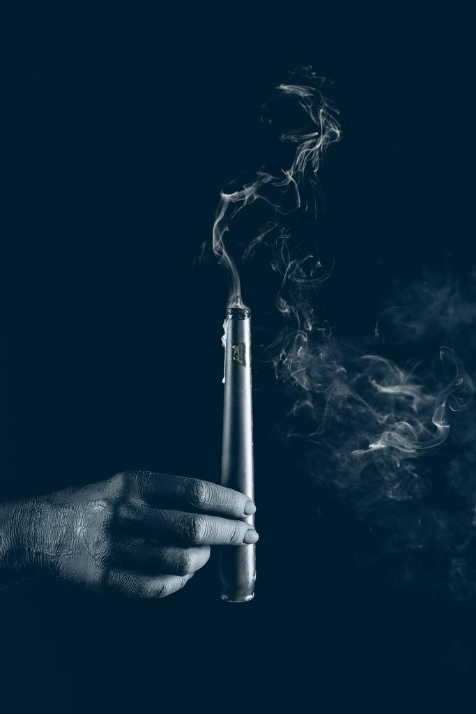 vista cortada da mão preta com vela fumegante, isolado em preto
 - Foto, Imagem
