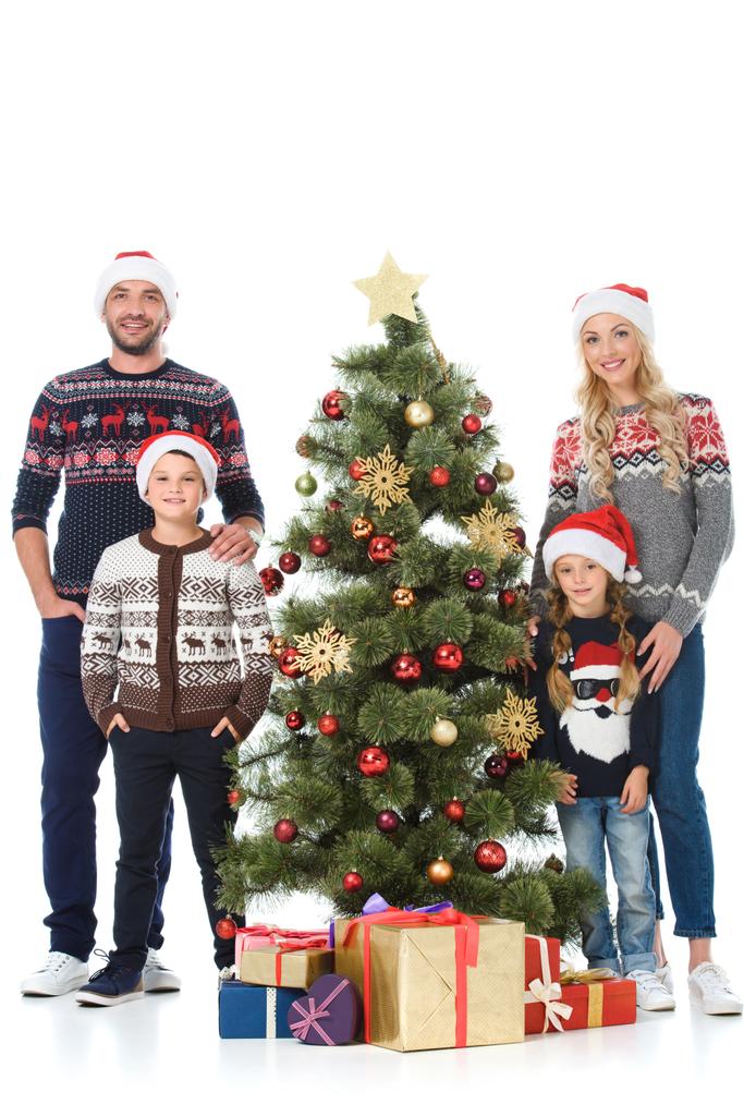 щаслива сім'я в капелюхах Санти, що стоять біля ялинки з подарунками, ізольовані на білому
 - Фото, зображення