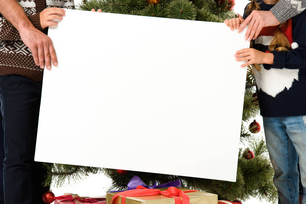 cropped view of family holding empty board against christmas tree - Photo, Image