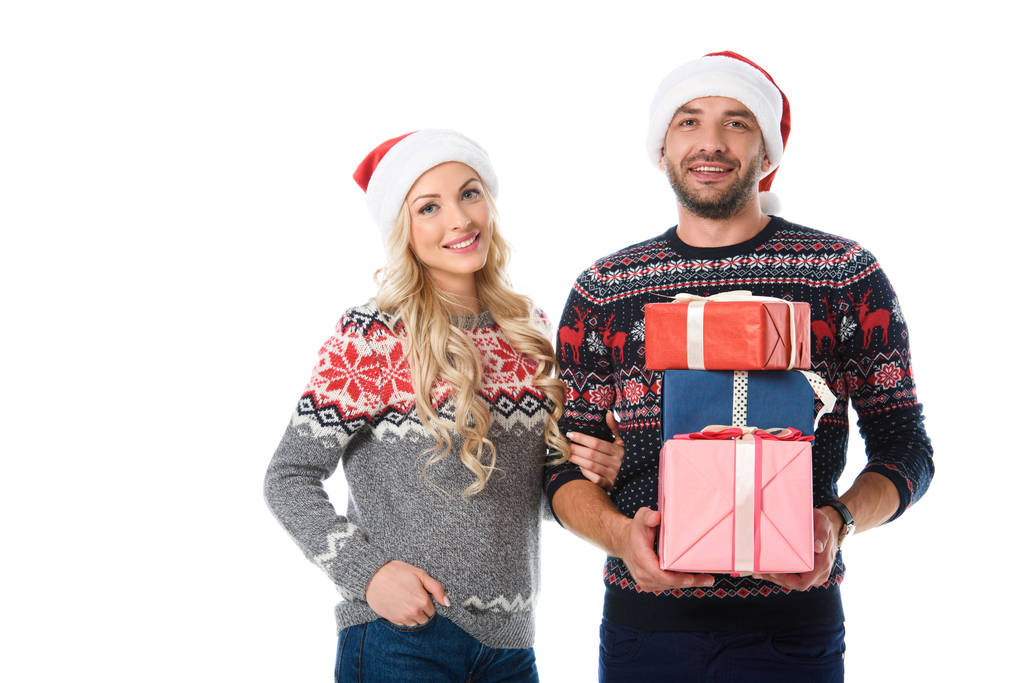 hymyilevä pari jouluna villapaidat ja santa hatut tilalla lahjoja, eristetty valkoinen
 - Valokuva, kuva