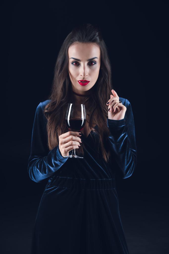 sexy vampire holding wineglass with blood isolated on black - Photo, Image