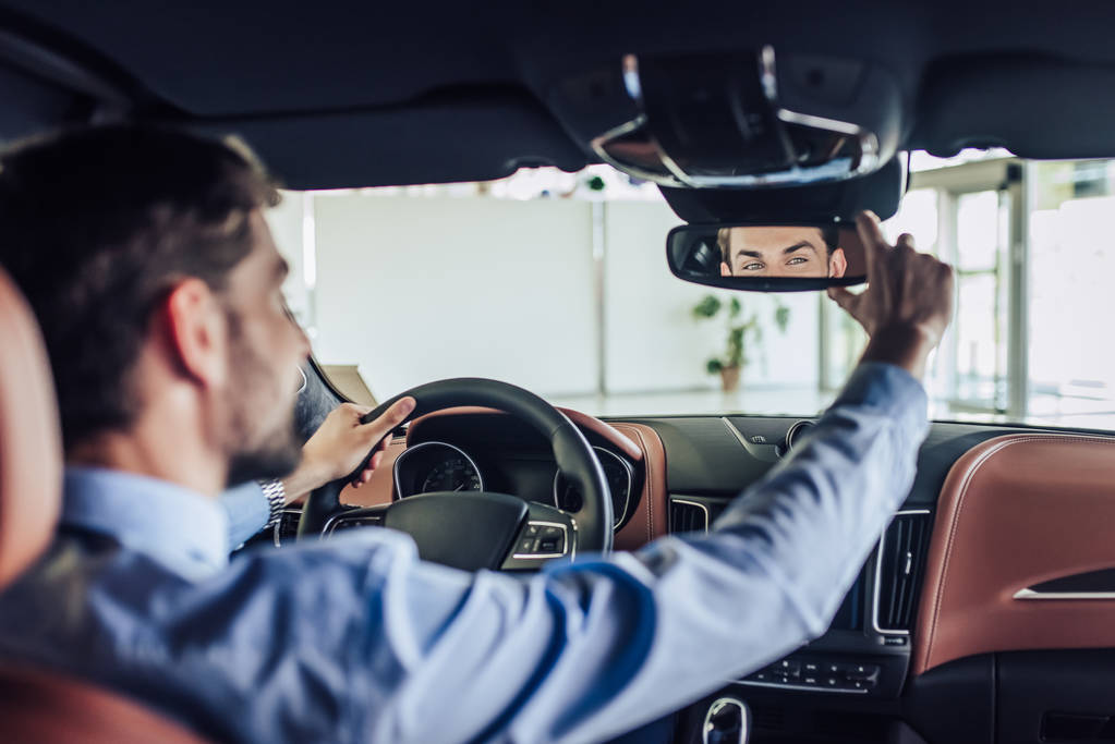 friont view of businessman adjusting the rear view mirror in car - Photo, Image