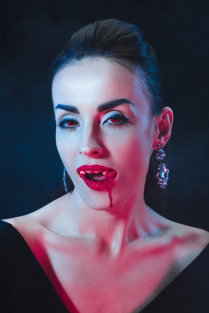 Kobieta sexy wampira lizanie jej usta na ciemnym tle - Zdjęcie, obraz