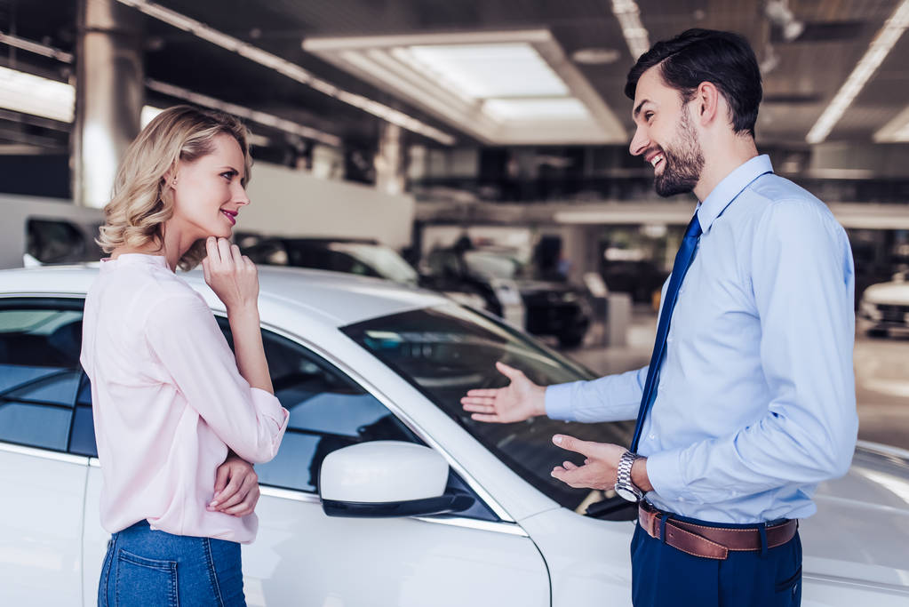 Kundin und Verkäuferin betrachten Neuwagen im Autohaus-Salon - Foto, Bild