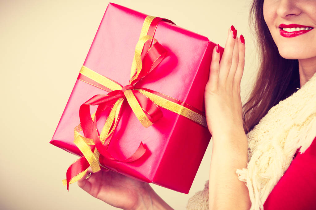 Cheerful woman holding present big red gift box. Christmas season celebration concept. Toned image - Photo, Image